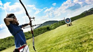 boy-practicing-archery-field-against-sky